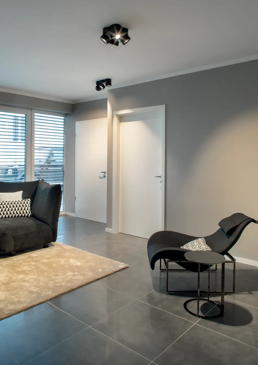 Spot Noxx 4 in Schwarz an der Decke eines Wohnraums mit Lounge Sessel Spot Noxx 4 in Schwarz an der Decke eines Wohnraums mit Lounge Sessel